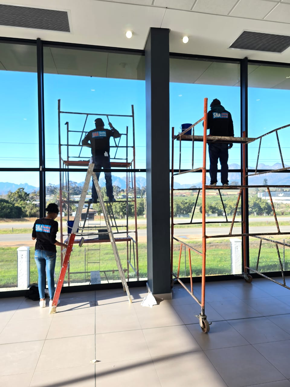 SNA team cleaning large office windows from scaffolding